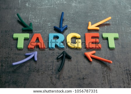 Business target plan or goal for success concept, multi colorful magnet arrows pointing at wooden letters the word TARGET at the center on chalkboard loft cement wall.