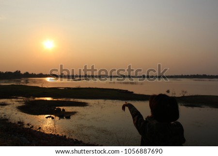 
Small children, brothers and sisters standing beside the river at dusk, with golden sun, taking a blurred photo