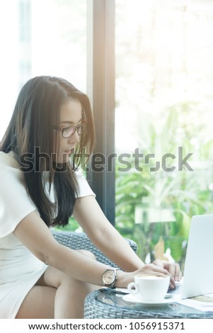 Beautiful asian attractive woman has working and typing on laptop computer for business marketing at coffee cafe in the morning with happy and relaxing time.
