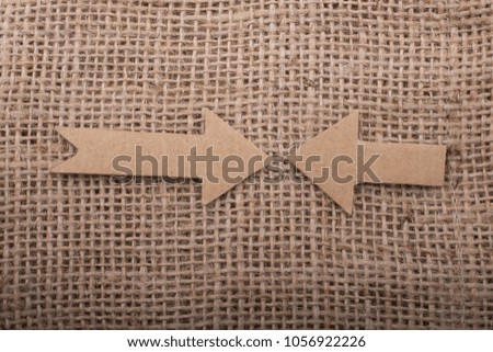 Arrows sign cut out of brown paper on canvas