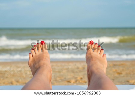A picture of the feet of a young woman lying on a beach in a tan. Beach vacations by the sea