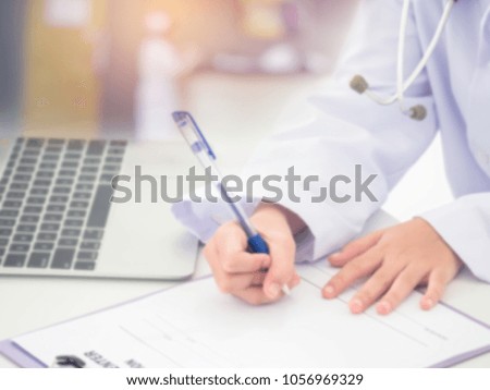 Blurred image of doctor writting on chart with using laptop at hospital. Healthcare and Medical concept.