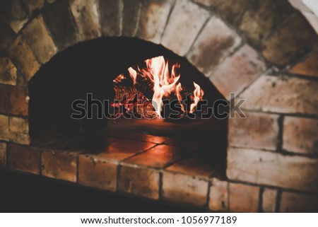 The vintage traditional oven makes from brown bricks with flame and firewood for cooking or baking pizza or yummy bread when the food cook in the oven, it makes nice smell, copy space, fire background