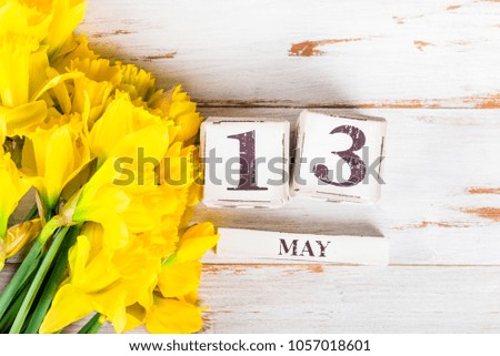 Wooden Blocks with Mothers Day Date, 13 May, for the year 2018,  Narcissus Flowers nearby
