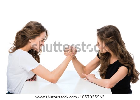 side view of angry twins armwrestling at table isolated on white