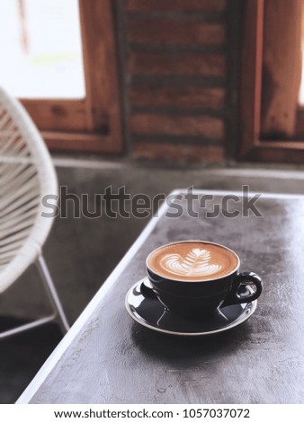 Cup of cappuccino coffee with beautiful flower latte art in loft atmosphere. Hipster tone. Blurred background, selective focus.