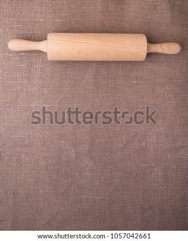 Vertical picture of a rolling pin on a rustic vintage table cloth with a copy space for text. Top view