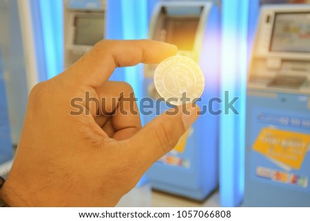 Man holding a bitcoin on a blurred ATM atm background.The concept of using digital currency.