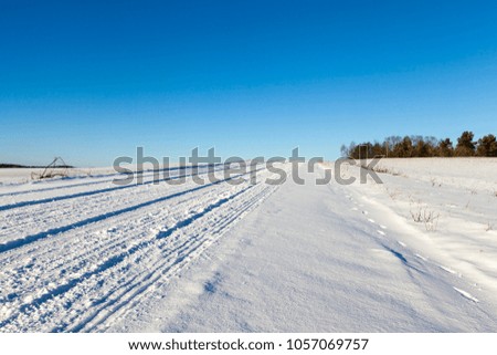 road in the winter season covered with snow. Photo taken close-up from the side of the road. Blue sky in the background