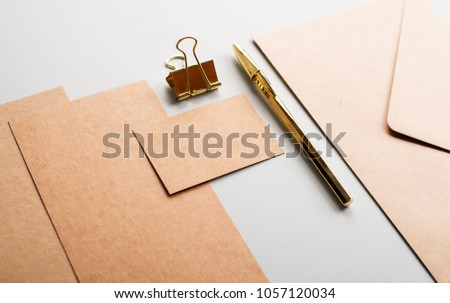 Top view of cards, envelope, business card in brown color with clip and golden ball pen on gray background. Mockup.