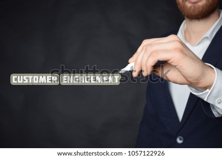The businessman writes an inscription with a white marker:CUSTOMER ENGAGEMENT