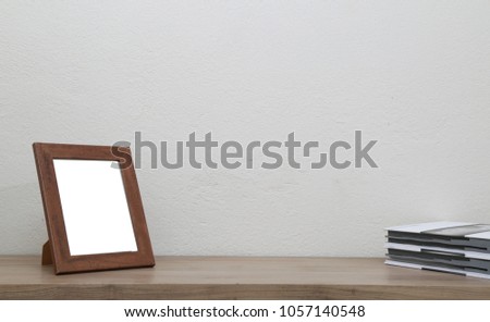 Desk with blank brown picture frame and  books.
