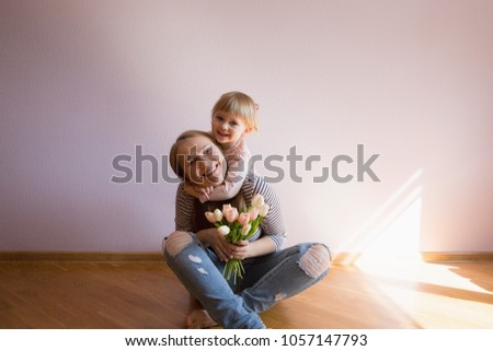 Happy family. Daughter gives a bouquet of flowers (tulips) to her mother in the room. Naturally laughed. Mother's Day.