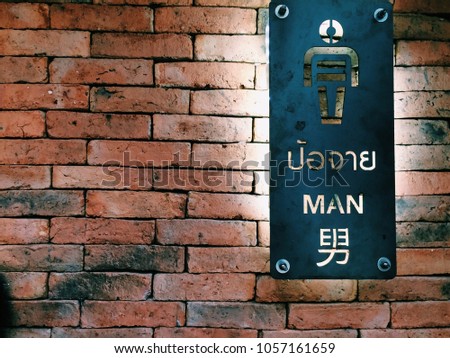 Men’s toilet sign made of stainless steal on red brick wall.