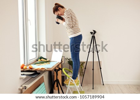 Woman taking picture of cut fruits and palm leaf on window sill. Food photography