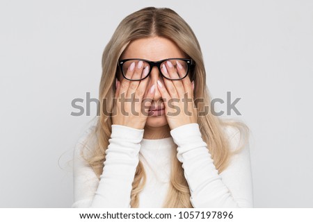 Sleepy young caucasian businesswoman in eyeglasses rubbing her eyes, feels tired after working on laptop, isolated on grey background.Overwork, tired, health concept.Exhausted, fatigue eyes
 Royalty-Free Stock Photo #1057197896
