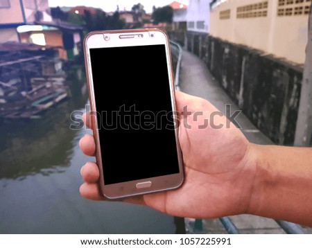 hand holding Mobile phone at outdoors on the Canal background. with blank copy space scree for your advertising text message or promotional content. For Graphic display montage.