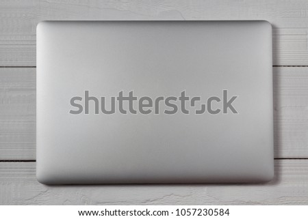 White closed laptop on wooden table background. Stiduo shot. Royalty-Free Stock Photo #1057230584