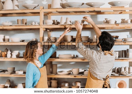two potters with ceramic dishware in workshop