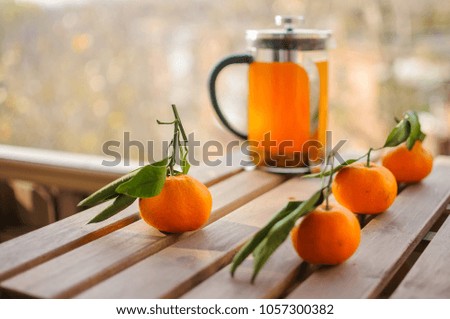 Glass teapot with orange drink and tangerines