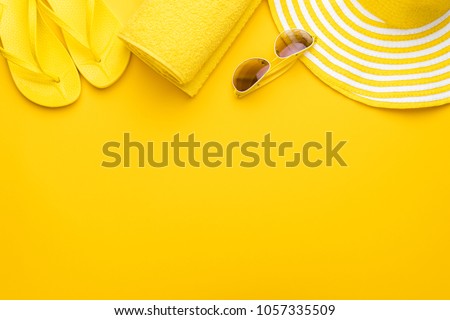 beach accessories on the yellow background - sunglasses, towel. flip-flops and striped hat. summer is coming concept Royalty-Free Stock Photo #1057335509