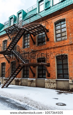 Snow on the street. Brick houses with stairway