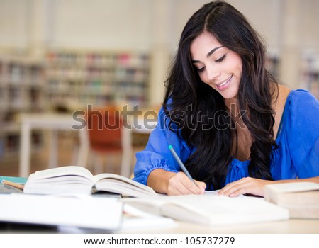 Female student studying at the library and smiling