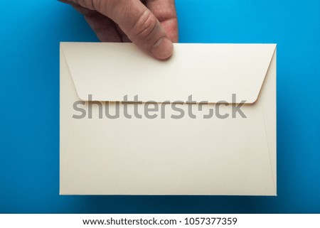 Blank envelope in hand isolated on blue background.