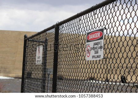 Danger high voltage sign on chain fence at water dam park