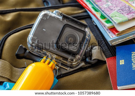 Conceptual picture of tourism, camera action, selfie stick, planning trip with map, passport, mobile phone on backpack background.