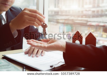 real estate agent holding house key to his client after signing contract,concept for real estate, moving home or renting property
