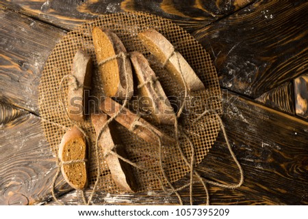 Conceptual still life photography of pieces of bread tied with twine, lying on an ancient wooden table made of rough boards on a round grid. Bakery, commercial, advertising design. Copy space