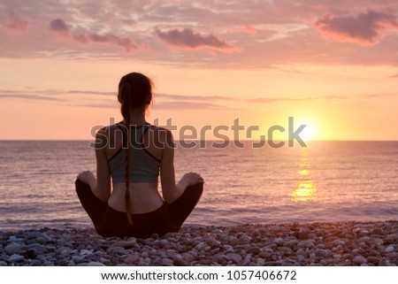 Woman meditating on the beach. Sunset