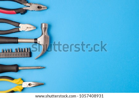 Tools worker, hammer, screwdriver, pliers on a blue background, top view Royalty-Free Stock Photo #1057408931