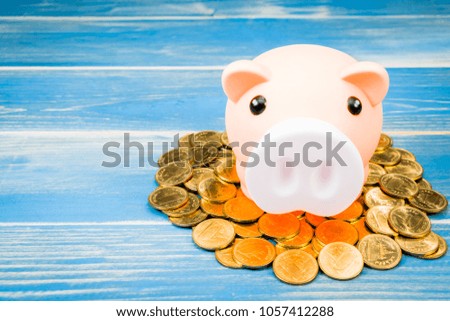 Piggy bank put on the gold coin to success with saving money as destinations on wood vintage blue background, To victory of business and investment for plan the future concept.