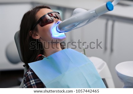 Teeth whitening for woman. Bleaching of the teeth at dentist clinic. Royalty-Free Stock Photo #1057442465