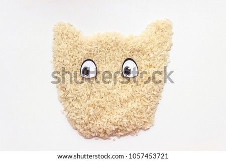 Rice groats are poured on a white background in the form of a cat with eyes