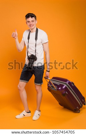 Take a vacation for relax! Full length picture of the young handsome man is going to travel with his professional camera and baggage. 