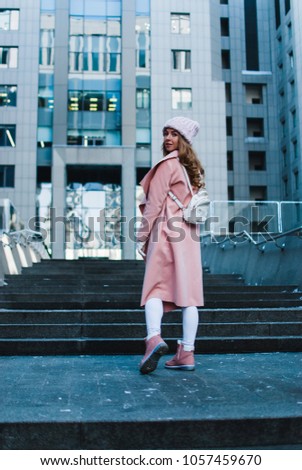 Wanna join me? Full length rear view of young woman in pink coat looking away while standing outdoors.
