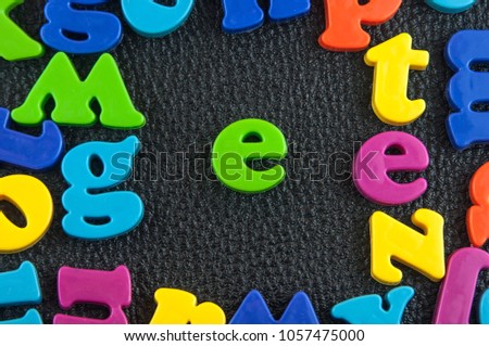 Plastic alphabet letter E on the leather background