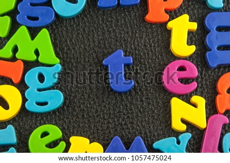 Plastic alphabet letter T on the leather background