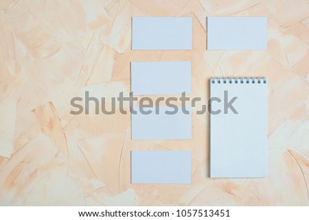 Photo of blank business cards, notepad on a light background. Layout for brand identification.