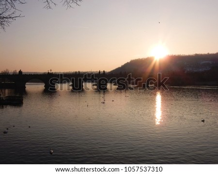 Panoramic view of Charles bridge in sunset with light reflecting in the river, Prague