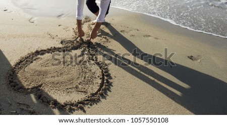 Fragment photo of man drawing heart on sand.Image of a heart drawn in the sand. 