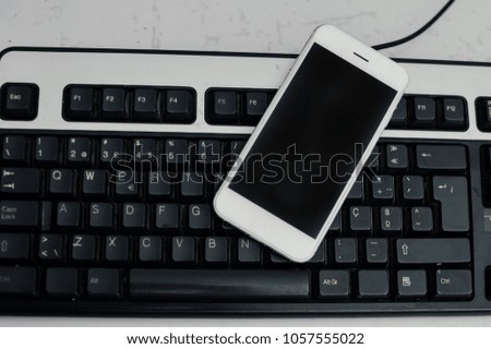 Mobile phone and computer keyboard on light table, communication technology background. Digital concept or gadgets support service, close up top view of electronic devices