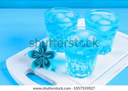 Blue cocktail with ice and mint in glasses on a white wooden board on a blue table