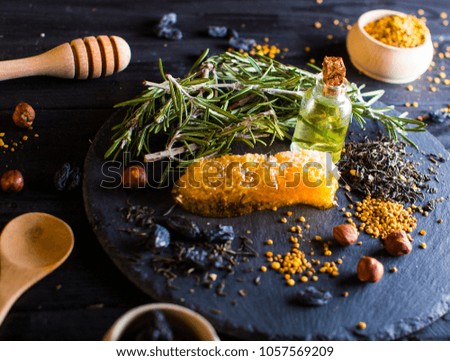 Honey sick. Oil bottle. Green leafs. Delicious food on blur studio kitchen table. Black plate and wooden brown table. Professional photo session. Professional photo studio.
