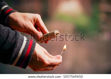 Close up of man hand lighting up a firecrackers in a burred background Royalty-Free Stock Photo #1057569650