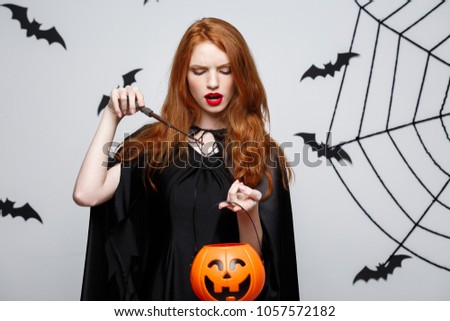 Portrait of beautiful caucasian witch holding orange pumpkin for celebrating Halloween.