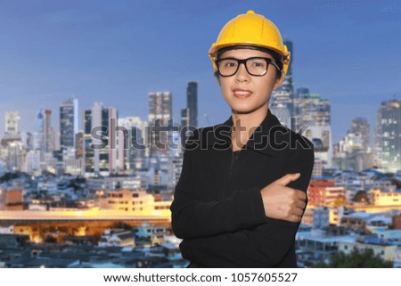 Engineering women in smiling happily and wear glasses on twilight city blur background and have clipping paths function for easy to use.